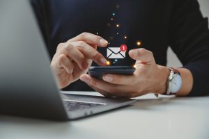 Hand of businessman using smartphone for email with notification alert after completing email lead capture form
